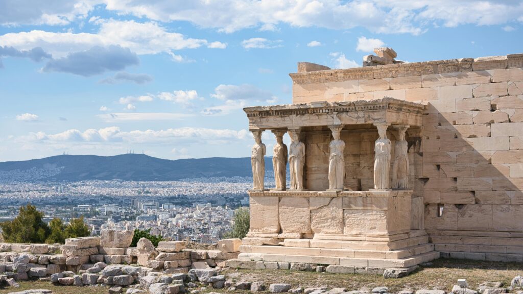 Ancient Erechtheion temple with Caryatids overlooking Athens, Greece under a blue sky.